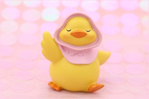 Close-up of cute yellow resin duck ornament with pink headscarf and smiling expression