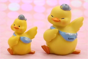 Detail of two cute yellow duck resin ornaments with blue 'SUPER' crossbody bags
