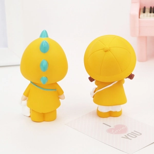 Rear view of cute yellow dinosaur and girl figurines on a desk with a toy piano