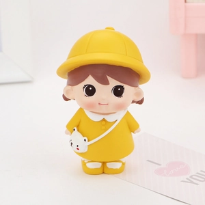 Close-up of a cute cartoon girl figurine in yellow dress with a bear bag for desk decor