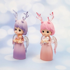 Macro shot of two resin angel girl figurines with antlers and wings on a dreamy background