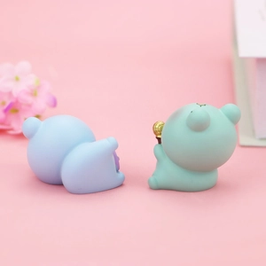 Makroansicht süßer Mini-Froschfiguren in Grün und Blau auf rosa Hintergrund