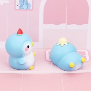 Close-up of two cute blue penguin figurines with fruit accessories for desktop decor