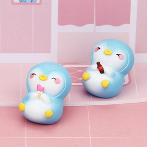 Close-up of cute blue resin penguin figurines holding a popsicle and drink for desk decor