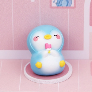 Cute blue penguin desk ornament holding a pink popsicle on a white circular base
