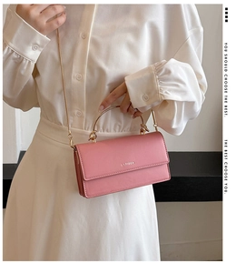 Detailopname van roze crossbodytas met goudkleurig metalen handvat en kettingriem