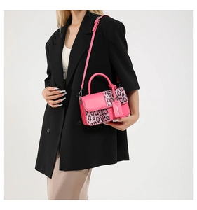 Detail of pink faux fur leopard print handbag featuring adjustable strap and leather tag
