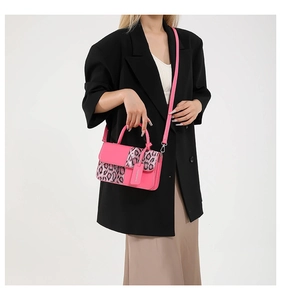 Detail of fuchsia pink handbag with leopard print flap and adjustable shoulder strap