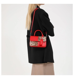 Detail of red leather leopard print handbag with fashion tag worn by model in black blazer