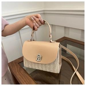 Detail of hand-woven straw crossbody bag with leather flap and metal keyhole lock