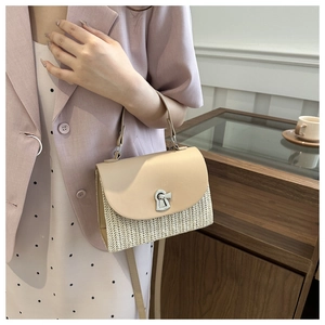Detail of hand-woven beige crossbody bag with smooth panels and silver twist-lock closure