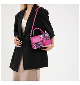 Detail of a bright pink crossbody bag with purple leopard print flap and fashion tag