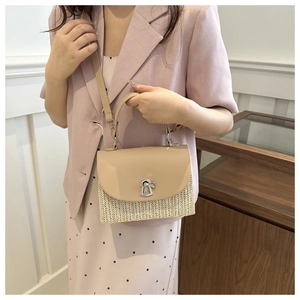 Detail of hand-woven straw crossbody bag with beige leather flap and silver twist lock