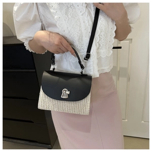 Detail of straw crossbody bag featuring black leather flap and silver metal buckle