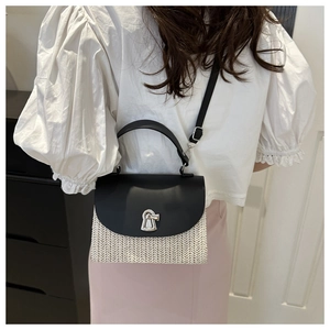 Detail of crossbody straw bag with black faux leather trim and silver metal lock closure