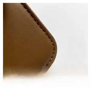 Detailed close-up of brown litchi grain leather texture and uniform stitching of the handbag