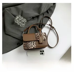Size comparison of leopard print crossbody bag next to a smartphone on a white desk