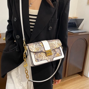 Retro snake-pattern crossbody bag with white leather trim and gold chain strap worn by model