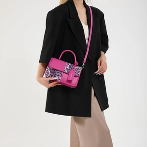Pink faux leather handbag with purple leopard print panels and top handle shown on model