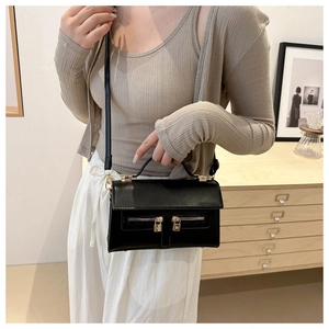 On-body view of a vintage black leather crossbody bag with dual zipper and gold lock detail