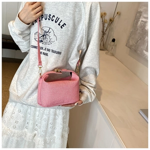 Detail of pink canvas crossbody bag with vintage gold metal clasp and textured fabric