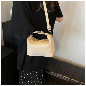 Close-up of the beige textured fabric shoulder bag with gold-tone hardware on a model