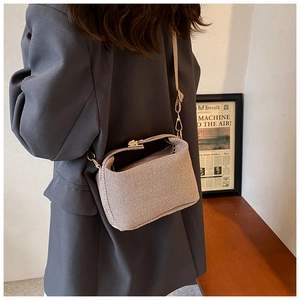 Close-up of stylish beige textured crossbody bag with gold metal hardware on model
