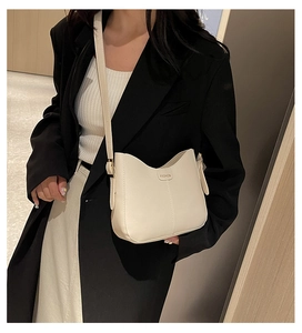 Model wearing a minimalist cream PU leather tote bag with elegant wavy edge design