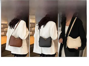 Three leather crossbody bags in brown, black, and beige colors with metal lettering