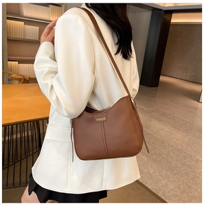 Brown faux leather shoulder bag with Fashion tag worn by a model in white blazer