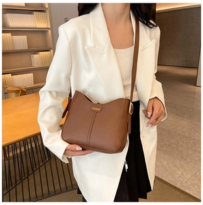 Brown PU leather crossbody bag with golden FASHION print detail on a model indoors