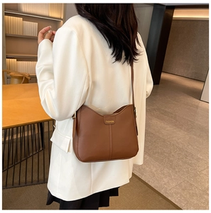 Detailed back view of model wearing the brown shoulder bag with a fashion logo plate