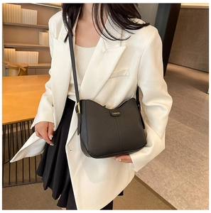 Detail of minimalist black matte leather saddle bag with fashion label and adjustable strap