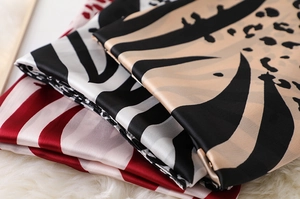 Detailed view of silk scarves with leopard print and stripes on a soft faux fur background