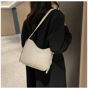 Close-up of beige lychee grain leather tote bag with gold logo on a female model