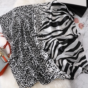 Detail of silk scarf with leopard and zebra print on white faux fur and marble surface