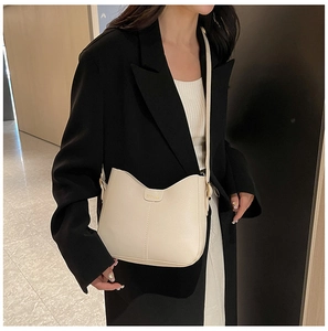 Detail of cream crescent crossbody bag with fine leather texture and golden logo accents