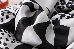 Macro shot of faux silk scarf with black and white animal print and wavy patterns