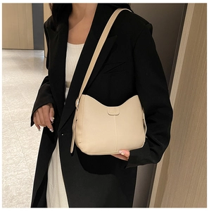 Detail of minimalist beige faux leather shoulder bag with fine stitching and gold logo