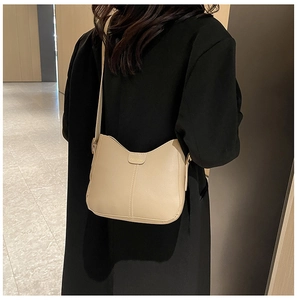 Detail of a beige leather tote bag with vertical stitching and FASHION buckle on a model