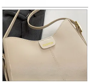 Detail of beige tote bag with white contrast stitching and gold buckle adjustment