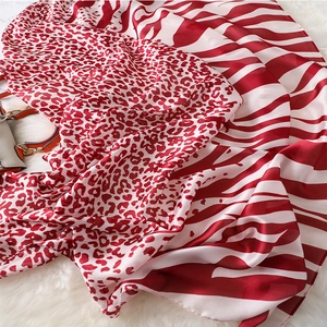 Close-up of red and white leopard zebra print silk shawl on white faux fur background