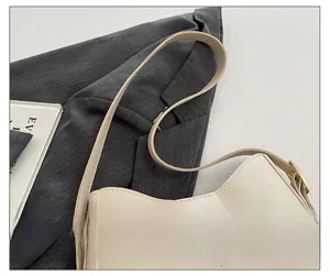 Detail of adjustable strap with gold buckle on cream faux leather crossbody tote bag