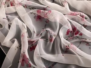 Detailed close-up of pearl white silk scarf with pink floral and dragonfly patterns