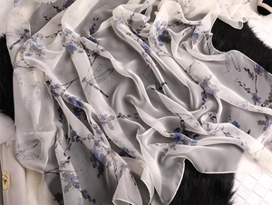 Detailed macro view of lightweight silk scarf with elegant dragonfly and blue floral prints