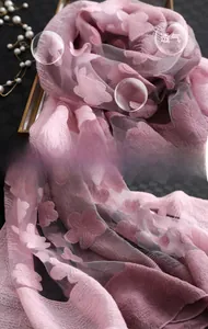 Détail macro du foulard en soie rose violet avec broderie 3D de fleurs et papillons