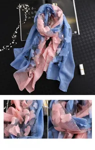Détail de la broderie florale rose et bleue sur foulard dégradé en soie à franges