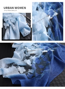 Détail macro d'une écharpe en soie dégradé bleu avec broderie florale et fines franges