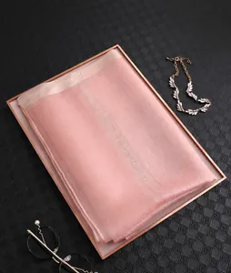 Detailansicht eines zartrosa Seidenschals mit Pailletten auf einem Metalltablett
