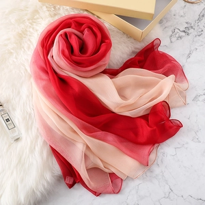 Sciarpa sfumata rossa e rosa in chiffon leggero elegantemente avvolta su sfondo bianco